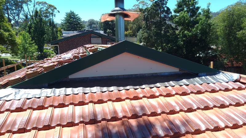The custom-made flashings sit on top of the sheet-lead and lower tiles.